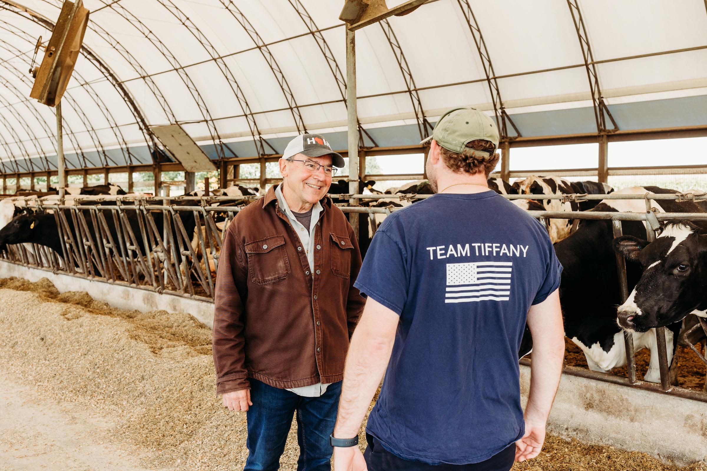 Tom Tiffany talking with a dairy farmer in a barn